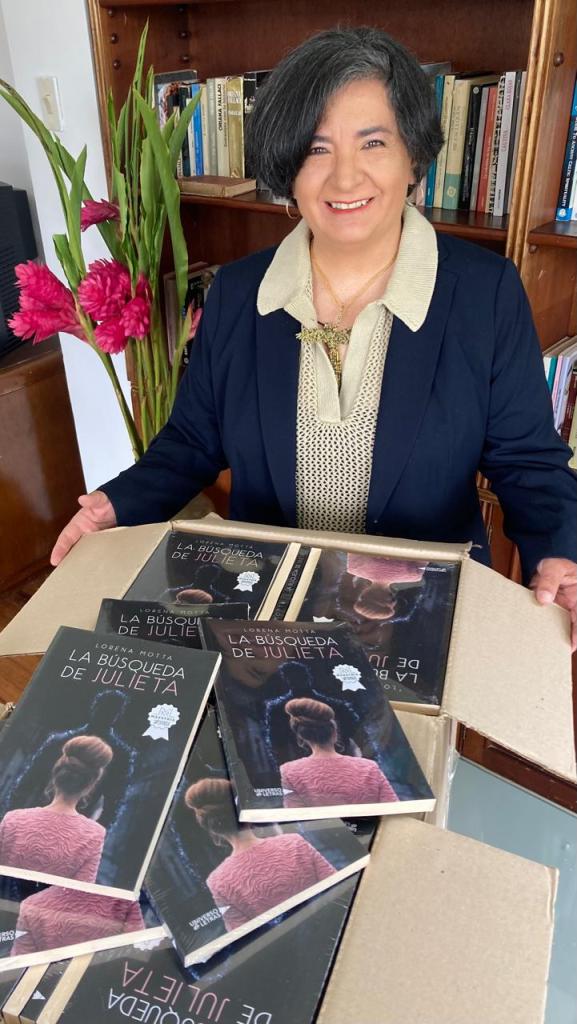 Lorena con la caja abierta y los libros a la vista, sonriendo de frente